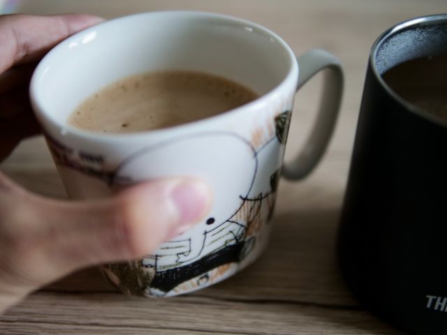 ホットコーヒー入りの陶器製マグカップを持つ